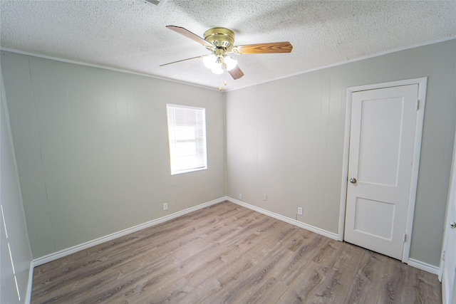 spare room with baseboards, ceiling fan, a textured ceiling, and light wood finished floors