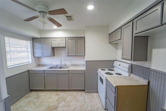 kitchen with wainscoting, light countertops, a sink, and white electric range oven