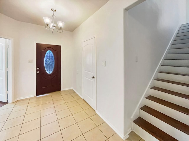 entryway with light tile patterned floors, stairway, baseboards, and an inviting chandelier