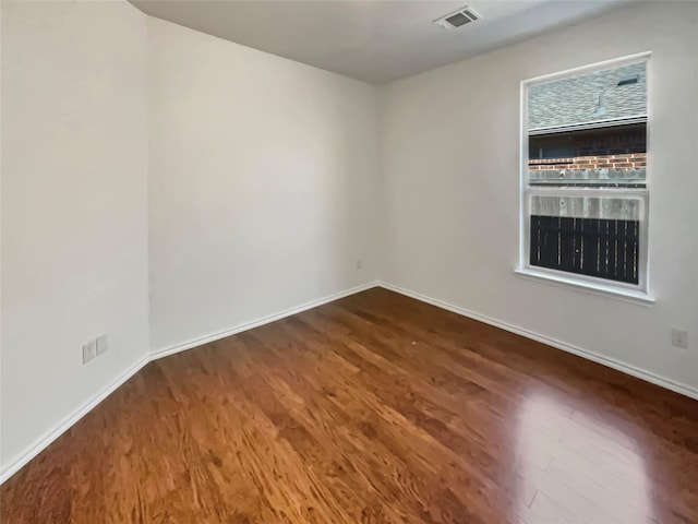 spare room with baseboards, visible vents, and dark wood finished floors