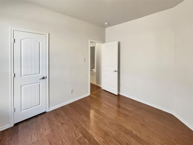 unfurnished bedroom with dark wood-style flooring and baseboards