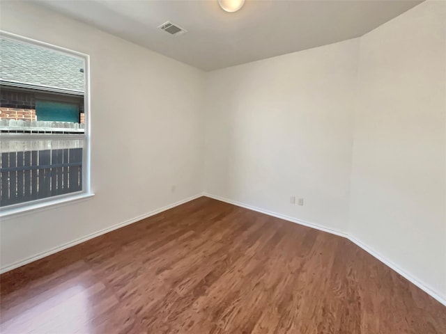 unfurnished room with baseboards, visible vents, and dark wood finished floors