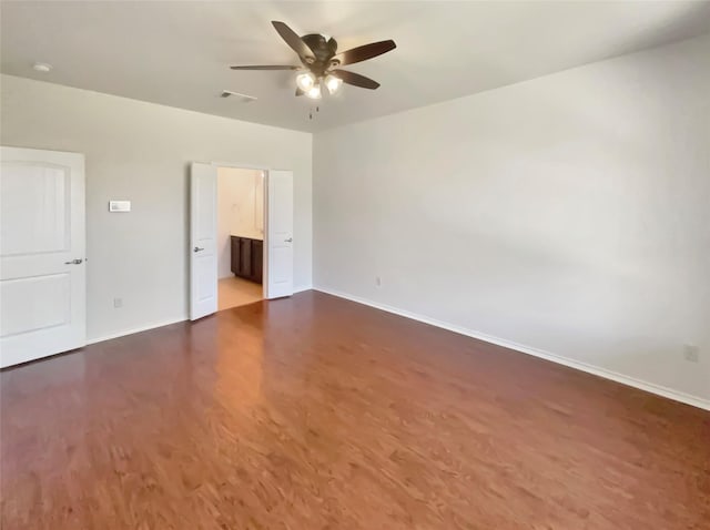 spare room with ceiling fan, visible vents, baseboards, and dark wood-type flooring