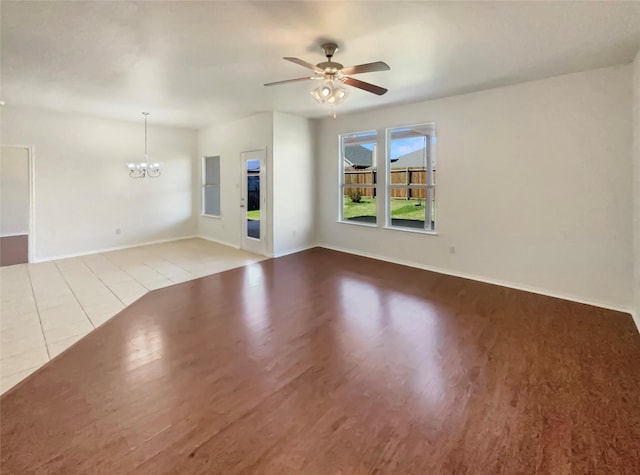 unfurnished living room with light wood-style flooring, baseboards, and ceiling fan with notable chandelier