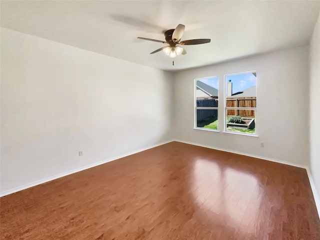 empty room featuring dark wood-type flooring, baseboards, and a ceiling fan