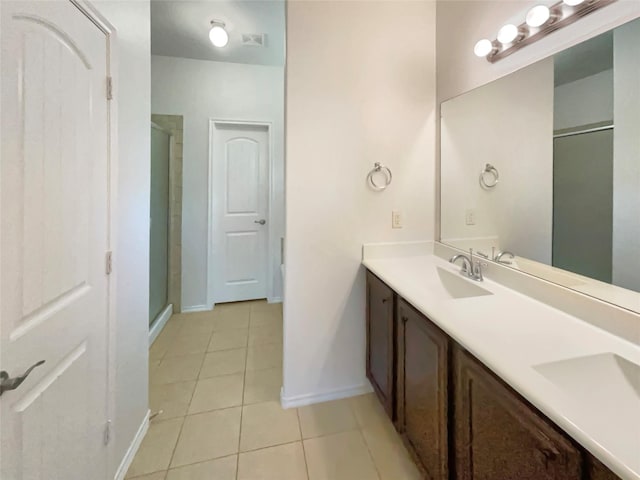 bathroom with a sink, double vanity, a stall shower, and tile patterned flooring