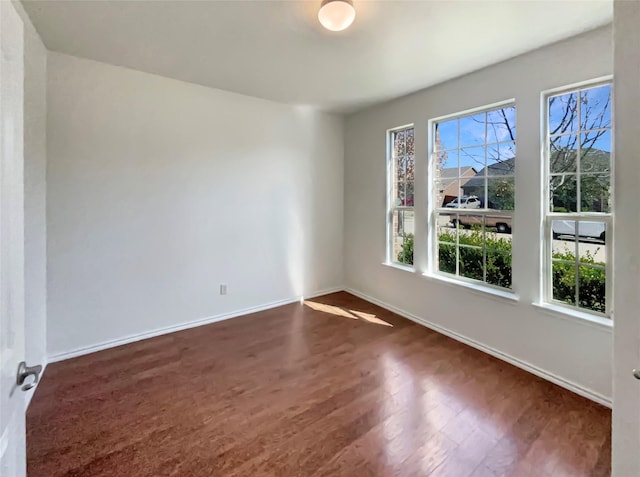 unfurnished room featuring dark wood-style floors and baseboards