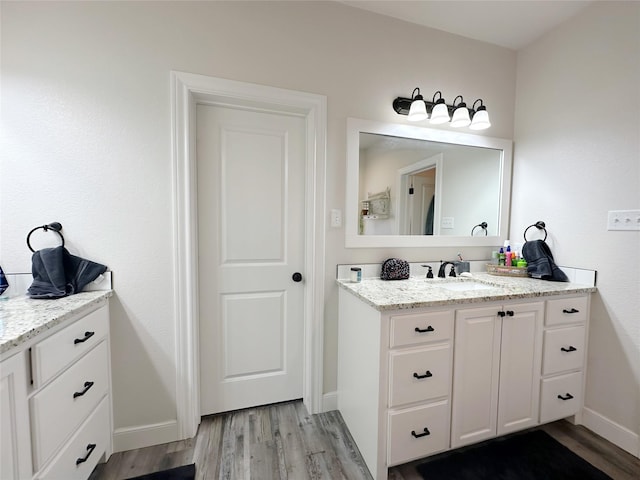 bathroom featuring vanity, baseboards, and wood finished floors