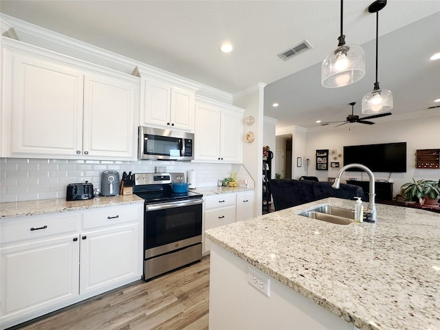 kitchen with stainless steel appliances, visible vents, open floor plan, white cabinetry, and a sink