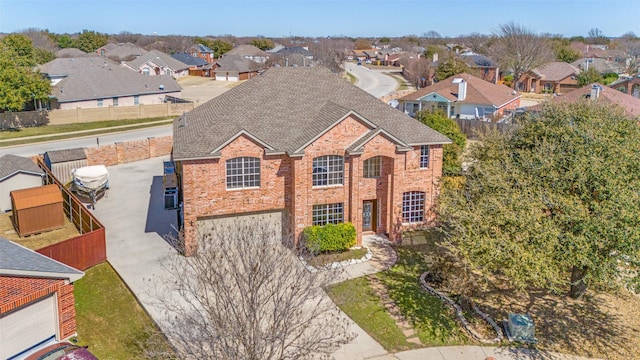 view of front of house featuring a shingled roof, concrete driveway, a fenced backyard, a residential view, and brick siding