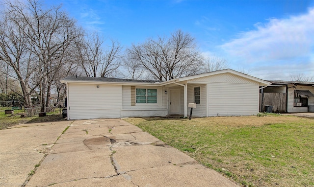 ranch-style house featuring a front lawn, concrete driveway, and fence