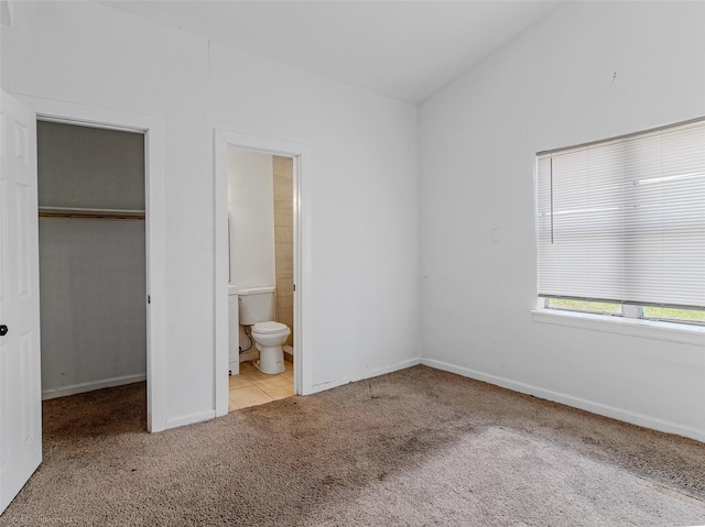 unfurnished bedroom with ensuite bathroom, a closet, carpet, lofted ceiling, and a spacious closet