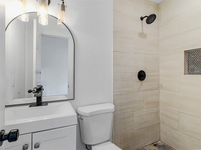 bathroom featuring toilet, vanity, and a tile shower