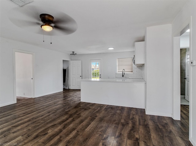 unfurnished living room featuring visible vents, a sink, dark wood finished floors, baseboards, and ceiling fan