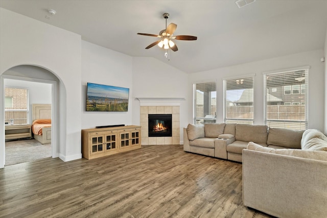 living area with visible vents, a tile fireplace, ceiling fan, wood finished floors, and vaulted ceiling