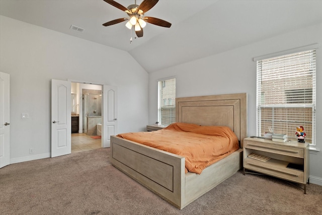 bedroom featuring multiple windows, vaulted ceiling, connected bathroom, and light colored carpet