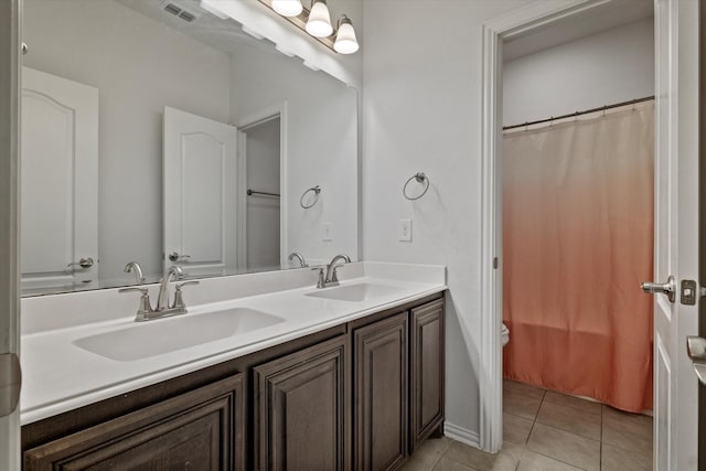 bathroom featuring double vanity, visible vents, a sink, and tile patterned floors