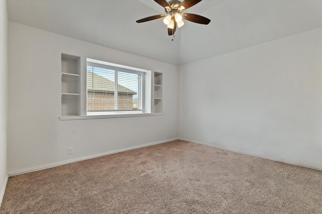 spare room featuring baseboards, built in features, a ceiling fan, carpet, and vaulted ceiling