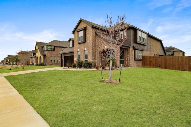 view of front of house with brick siding, fence, driveway, and a front lawn