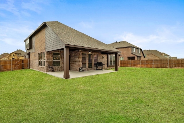 back of property featuring a fenced backyard, brick siding, a shingled roof, a yard, and a patio area