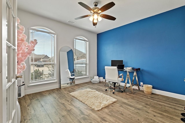 unfurnished office featuring ceiling fan, wood finished floors, visible vents, and baseboards