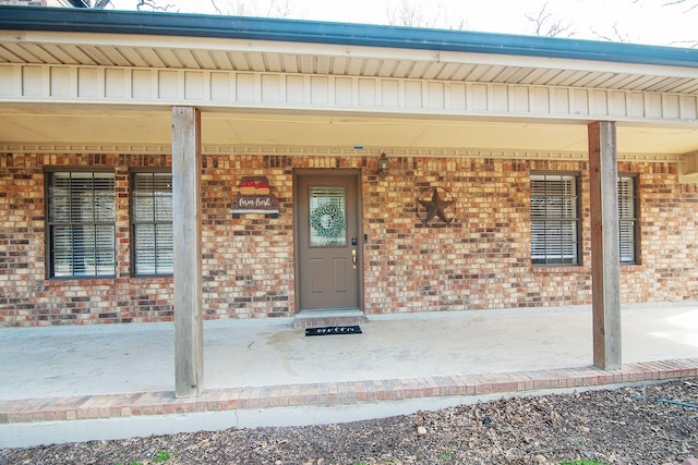 view of exterior entry featuring board and batten siding and brick siding