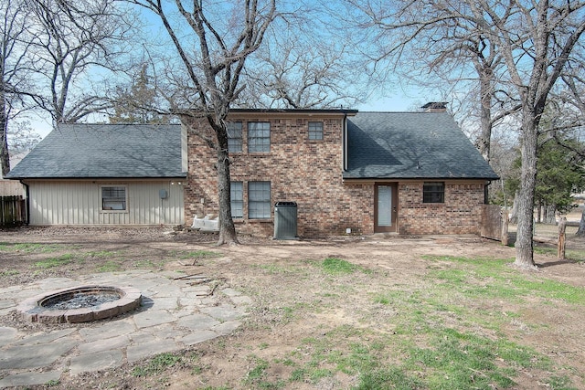 rear view of house featuring an outdoor fire pit, a chimney, a shingled roof, and brick siding