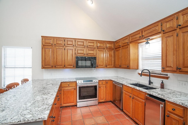 kitchen with brown cabinetry, light stone counters, stainless steel appliances, and a sink