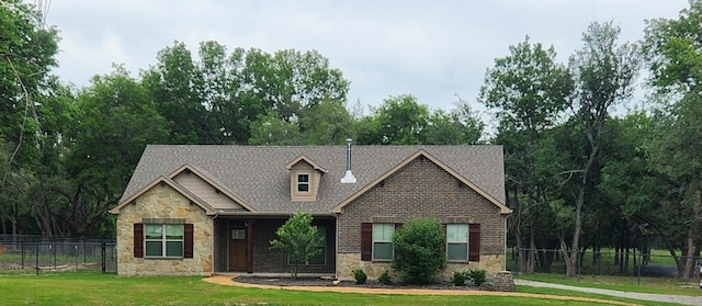 view of front of house featuring stone siding, fence, and a front lawn