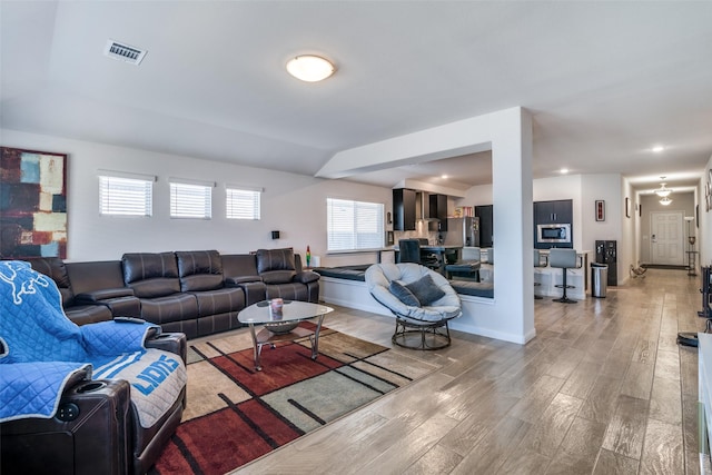 living room with baseboards, visible vents, and light wood-style floors