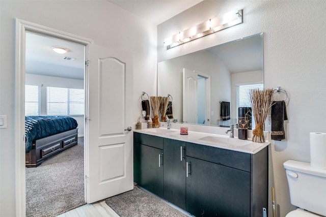 bathroom featuring a healthy amount of sunlight, double vanity, toilet, and a sink