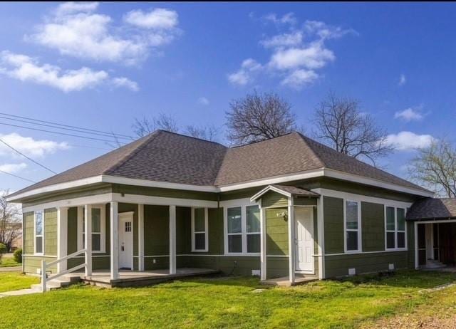 rear view of house with a shingled roof and a lawn