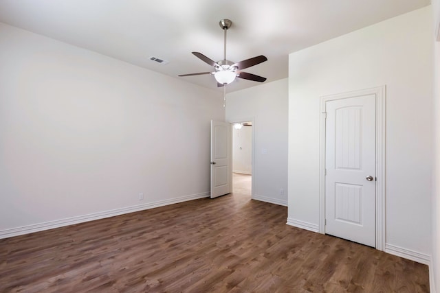 unfurnished bedroom featuring dark wood-type flooring, a ceiling fan, visible vents, and baseboards