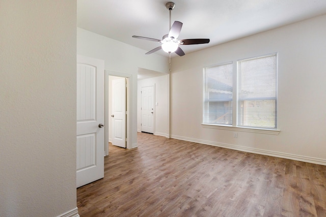 unfurnished room featuring a ceiling fan, light wood-style flooring, and baseboards