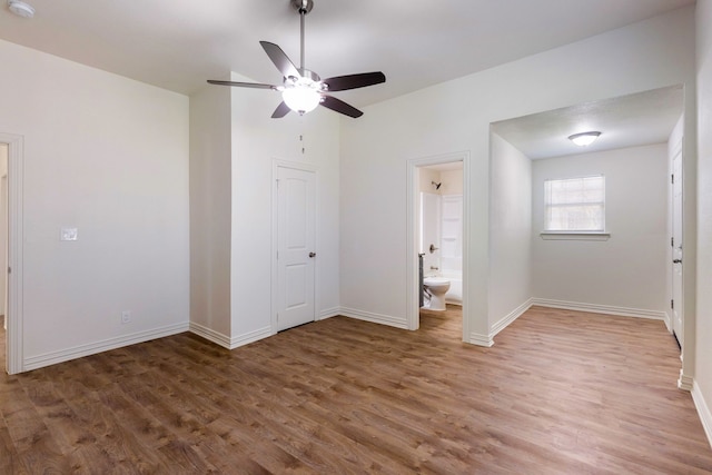 unfurnished bedroom featuring dark wood-type flooring, baseboards, and ensuite bathroom