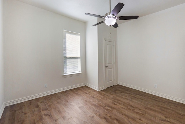 empty room with a ceiling fan, dark wood finished floors, and baseboards