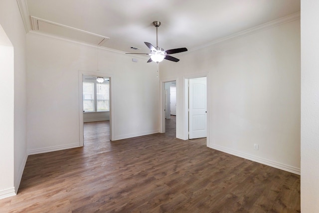 spare room featuring baseboards, attic access, ornamental molding, and dark wood-style flooring