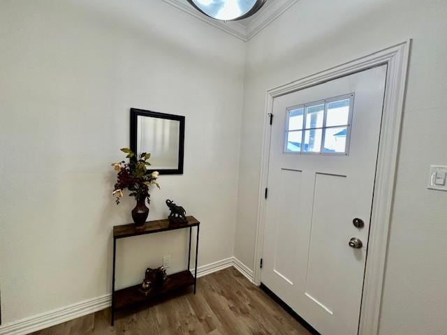 doorway with crown molding, baseboards, and dark wood-style flooring