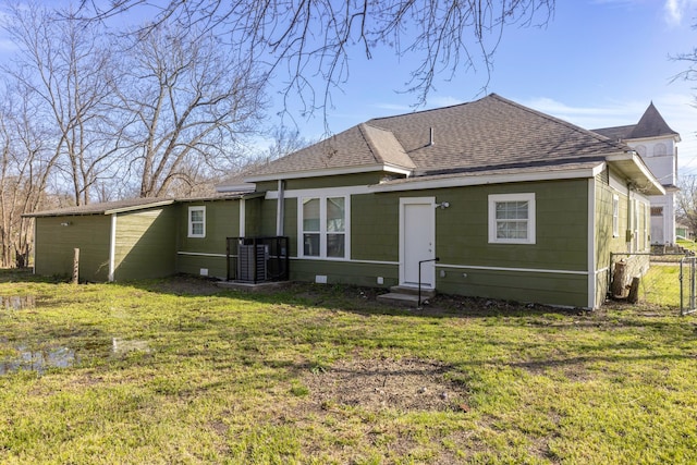 rear view of property with entry steps, a yard, roof with shingles, and fence