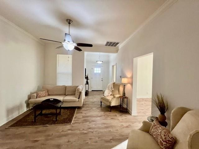 living area featuring visible vents, ornamental molding, a ceiling fan, wood finished floors, and baseboards