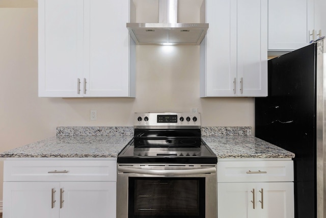 kitchen with stainless steel range with electric stovetop, wall chimney exhaust hood, white cabinets, and freestanding refrigerator