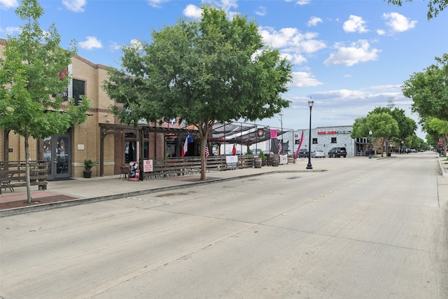 view of road featuring sidewalks, street lighting, and curbs