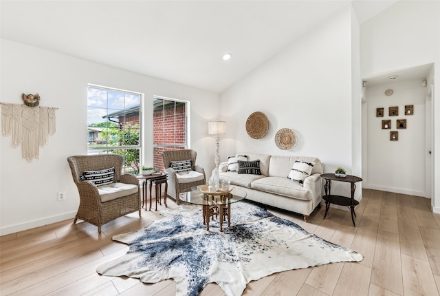 living area with light wood finished floors, baseboards, high vaulted ceiling, and recessed lighting