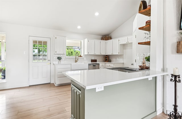 kitchen featuring a peninsula, a sink, and white cabinets