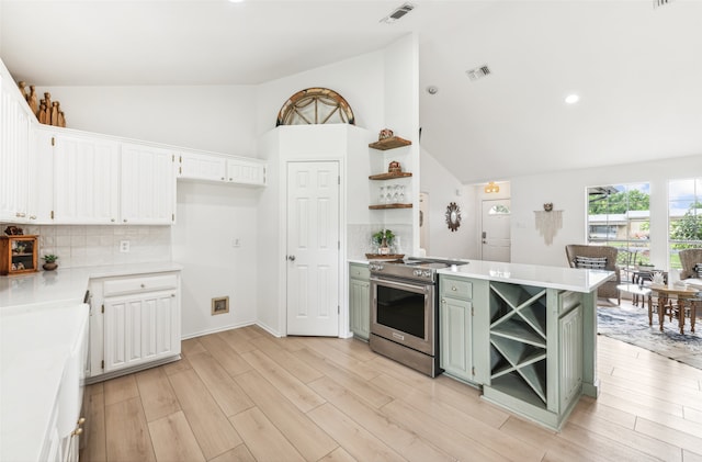 kitchen with electric range, open shelves, green cabinetry, and light countertops