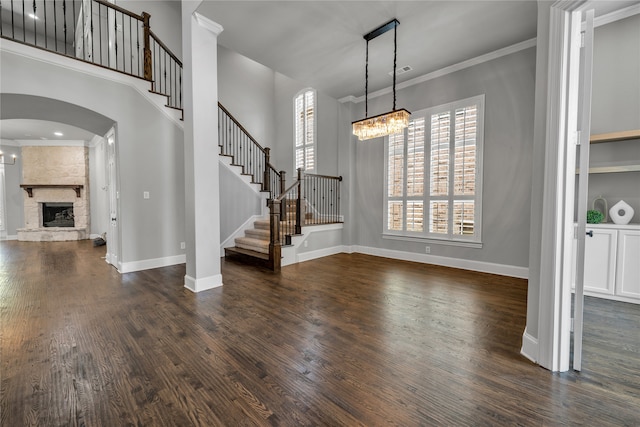 entryway featuring crown molding, a fireplace, dark wood finished floors, stairway, and baseboards