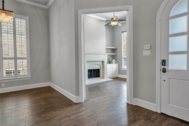 entrance foyer with dark wood-style floors, a fireplace with raised hearth, crown molding, and baseboards