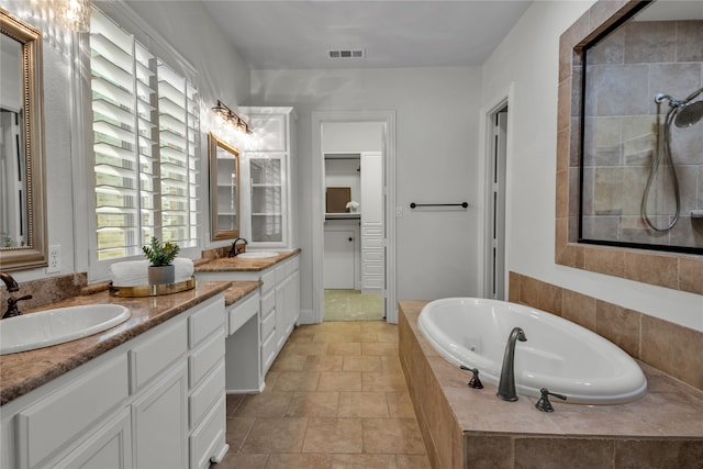 bathroom featuring a bath, double vanity, visible vents, and a sink