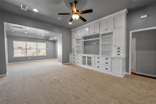 unfurnished living room with baseboards, visible vents, a ceiling fan, and light colored carpet