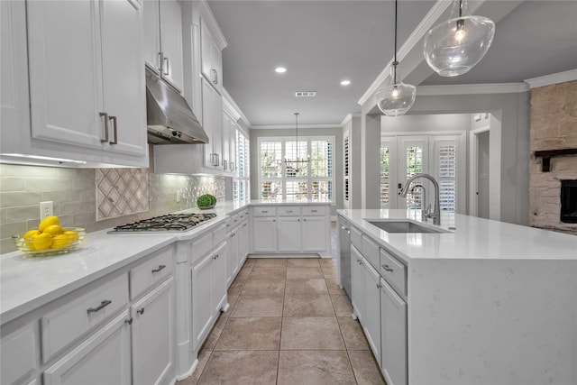 kitchen with under cabinet range hood, white cabinets, a sink, and decorative light fixtures